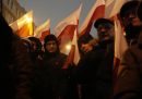 Un gruppo di uomini vestiti di nero con bandiere della Polonia, sostenitori del partito di destra Diritto e Giustizia, protestano davanti al Parlamento contro le misure del nuovo governo progressista