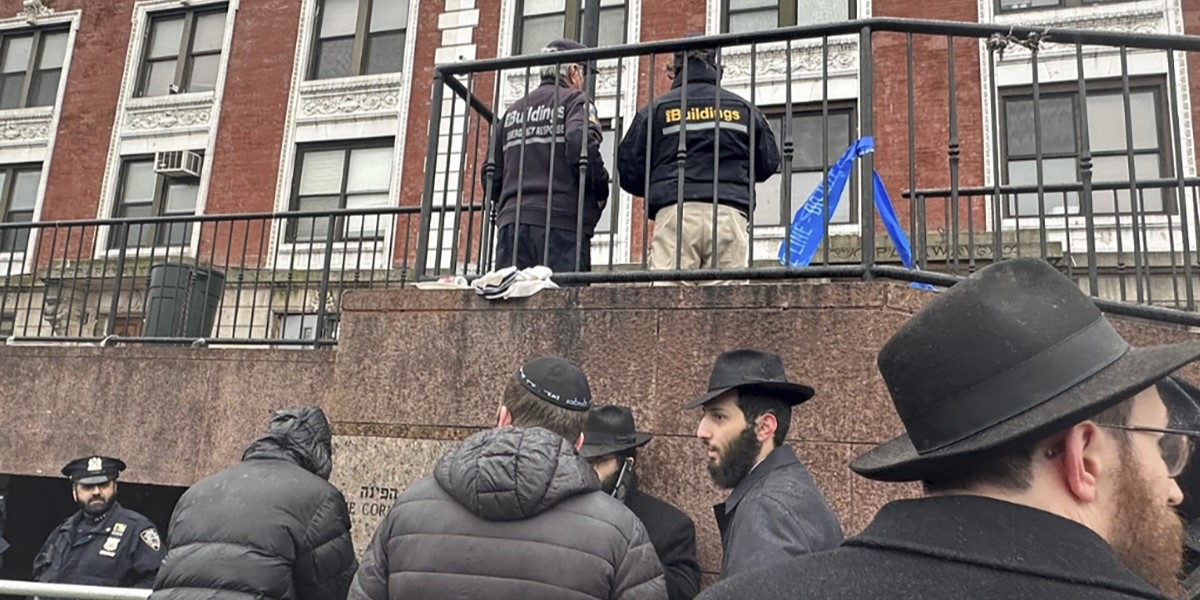 Ispettori, agenti di polizia e membri del movimento Chabad-Lubavitch fuori dalla sinagoga, lunedì (AP Photo/Jake Offenhartz)