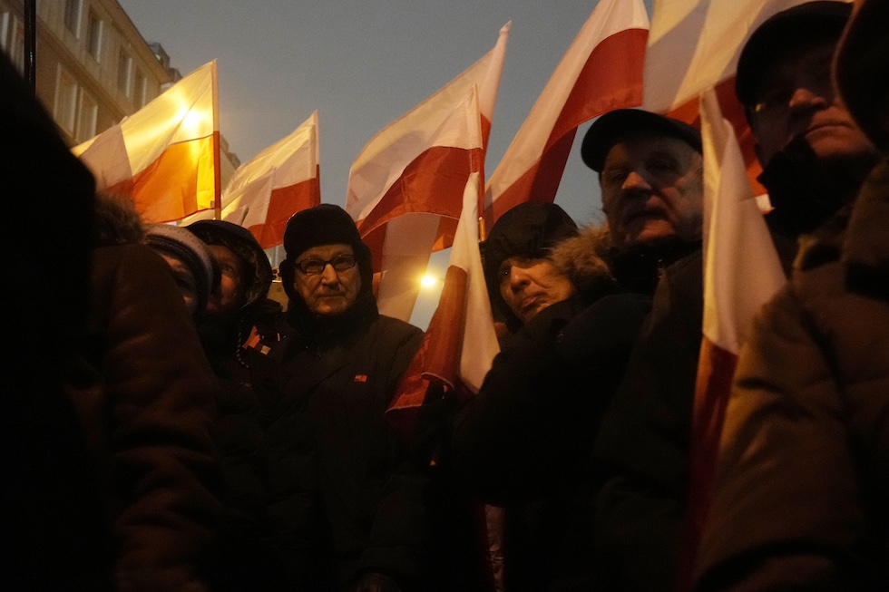 Un gruppo di uomini vestiti di nero con bandiere della Polonia, sostenitori del partito di destra Diritto e Giustizia, protestano davanti al Parlamento contro le misure del nuovo governo progressista