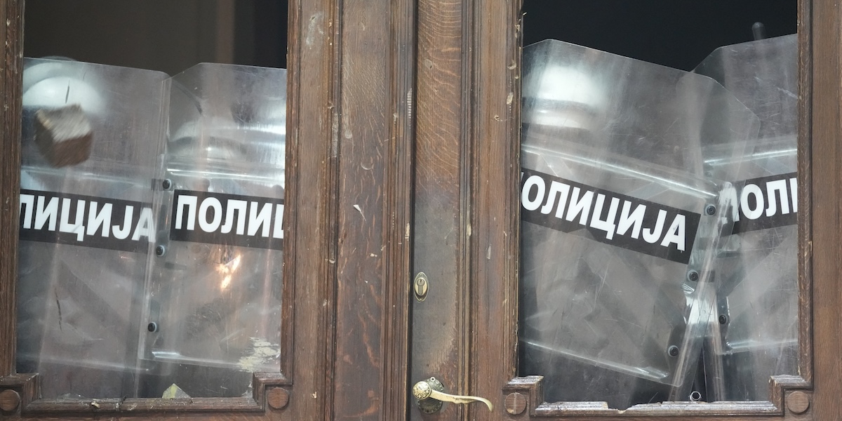 Una porta chiusa da alcuni agenti durante le proteste antigovernative a Belgrado (AP Photo/Darko Vojinovic)
