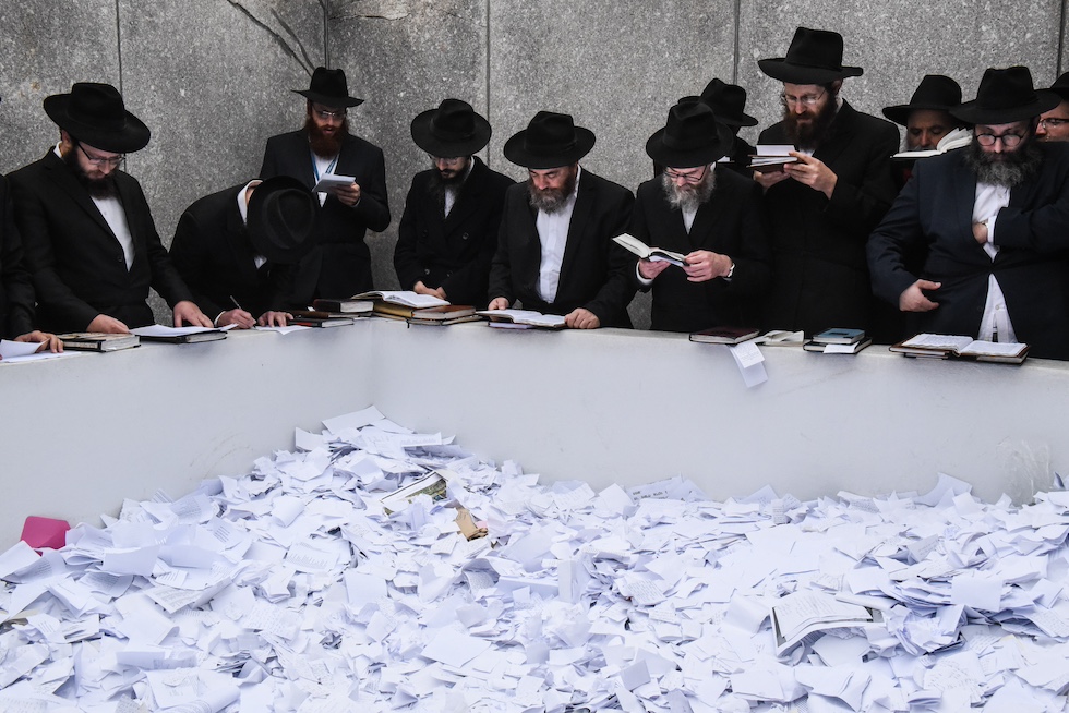 Ebrei chassidici pregano davanti alla tomba, piena di biglietti di carta con messaggi e preghiere, del Rebbe Menachem Mendel Schneerson, leader del movimento Chabad-Lubavitch, nel Vecchio Cimitero Montefiore nel Quees, a New York, nel 2018
