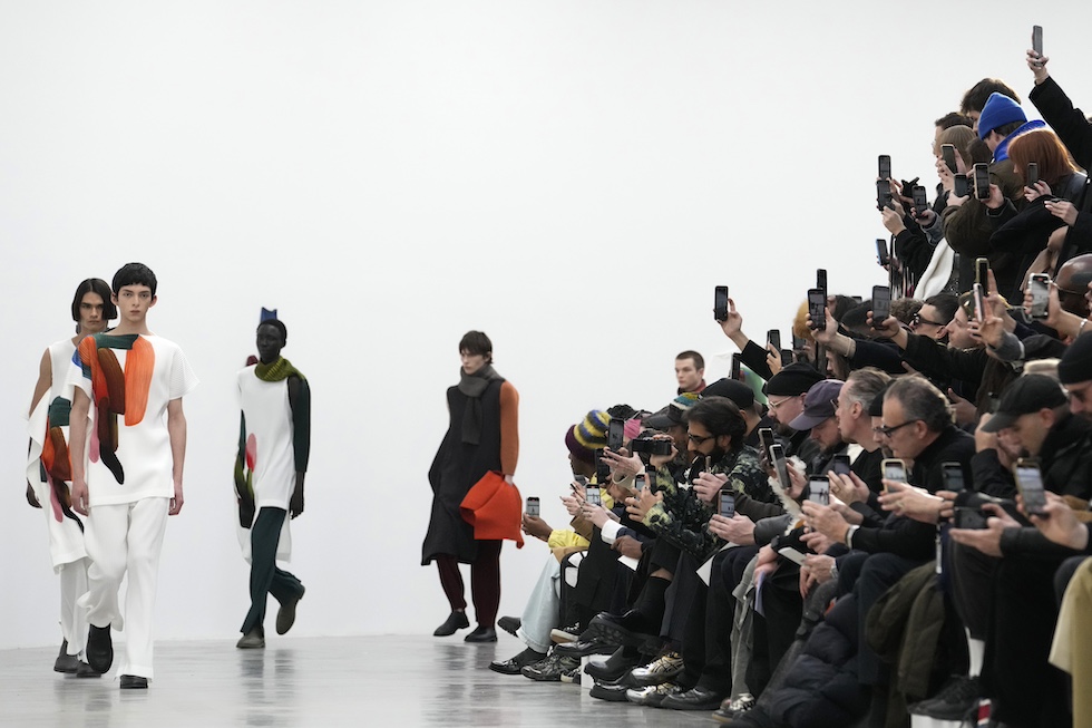 Nella foto dei modelli (a sinistra) sfilano davanti al pubblico che li filma (a destra) durante la sfilata dello stilista giapponese Issey Miyake durante la Fashion Week di Parigi per le collezioni di moda maschile Autunno-Inverno 2024-2025