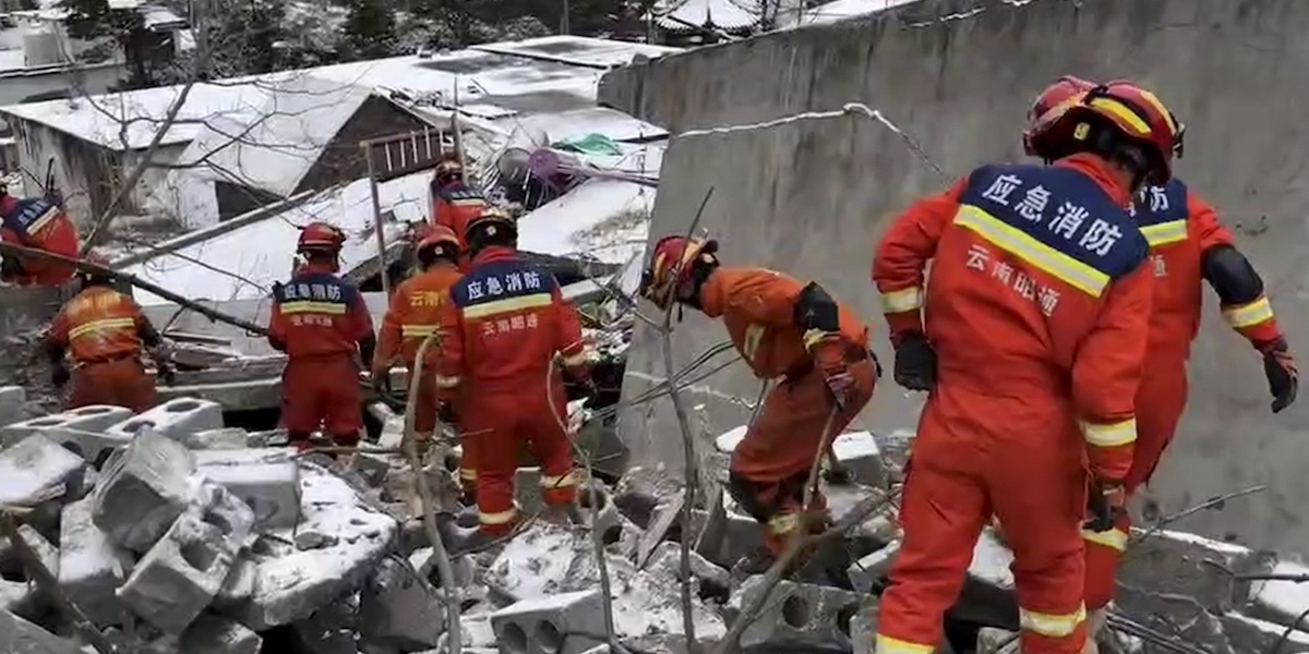 Alcuni soccorritori in tuta rossa mentre cercano le persone bloccate sotto alle macerie su cui si è depositata della neve