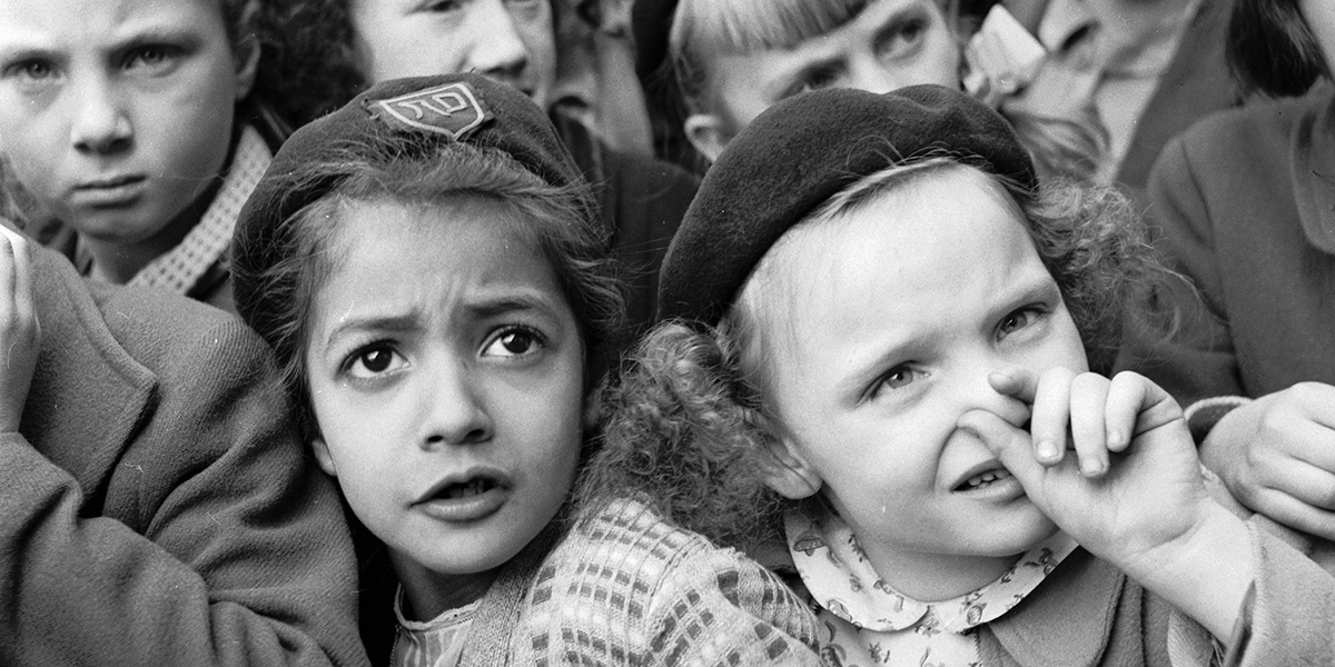 una bambina si tappa il naso con le mani, stretta in un gruppo di bambini che assistono a uno spettacolo a Parigi nel 1955