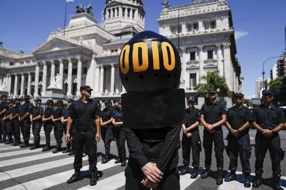 Una persona che indossa un casco con scritto "odio" davanti alla polizia schierata fuori dal Congresso a Buenos Aires 