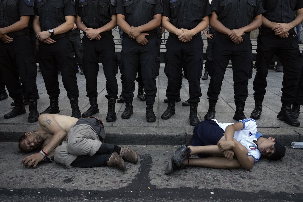 Un uomo e un ragazzo inginocchiati davanti alla polizia, davanti al Congresso