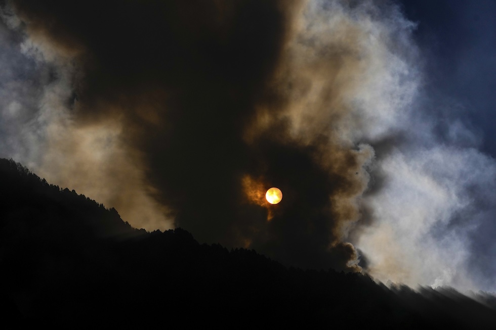 Il sole che sorge dietro alla collina di El Cable, mentre è in corso un incendio