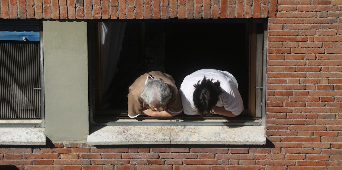 Foto di una signora anziana con la sua badante, entrambe affacciate alla finestra