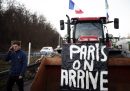 Un uomo cammina accanto a un trattore su cui è stato messo un cartello che dice "Parigi, stiamo arrivando" ad Argenteuil