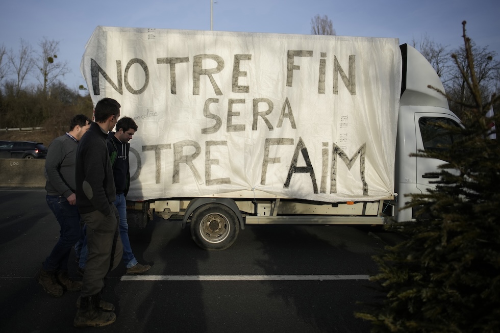 Agricoltori vicino a un camion su cui è stato scritto il messaggio "La nostra fine sarà la vostra fame" ad Argenteuil
