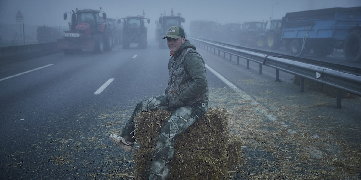 Un agricoltore siede su una balla di fieno durante un blocco dell'autostrada a nord di Tolosa, 25 gennaio 2024 (Kiran Ridley/Getty Images)