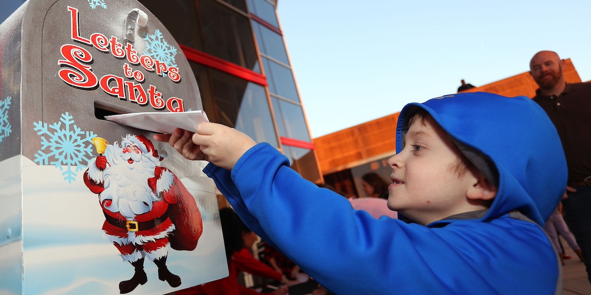 Un bambino imbuca una lettera in una cassetta per le lettere indirizzate a Babbo Natale