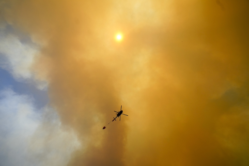 Un elicottero nel cielo rosso a causa degli incendi