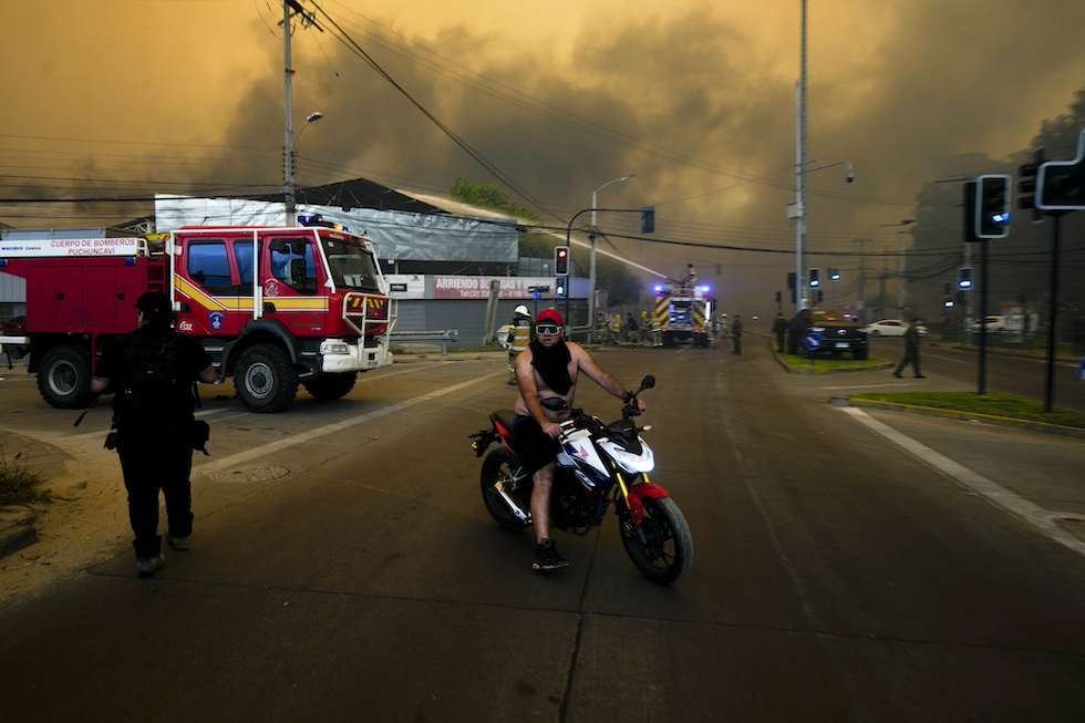 Un uomo in moto con il cielo rosso a causa degli incendi