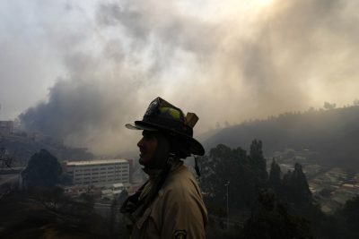 Il profilo di un vigile del fuoco con dietro il fumo degli incendi