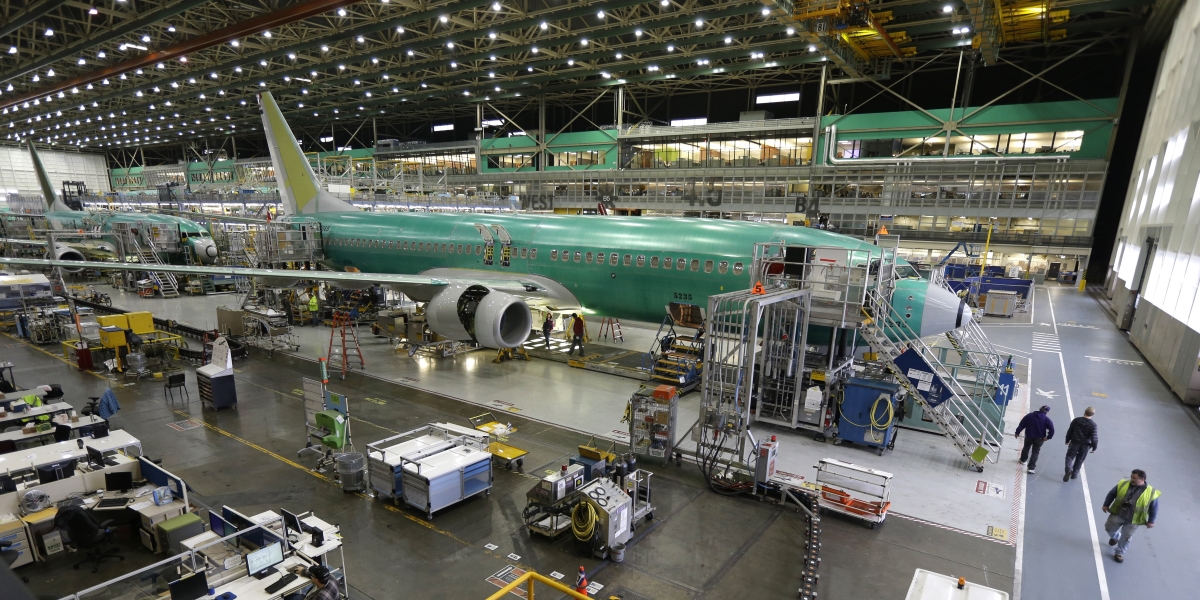 un aereo incompleto circondato da lavoratori, materiale e macchinari in un grande capannone
