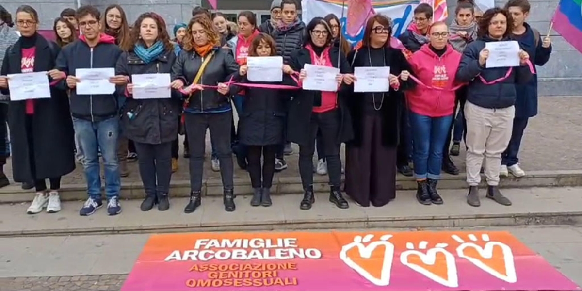 un gruppo di donne davanti a uno striscione con su scritto "famiglie arcobaleno"