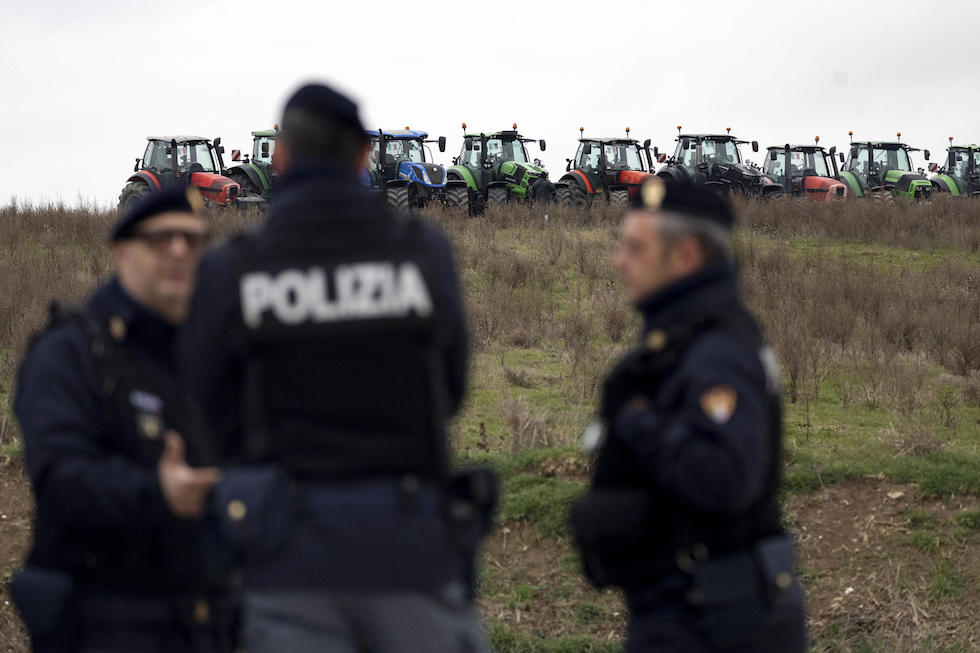 Foto dei trattori su una collina con agenti della polizia in primo piano