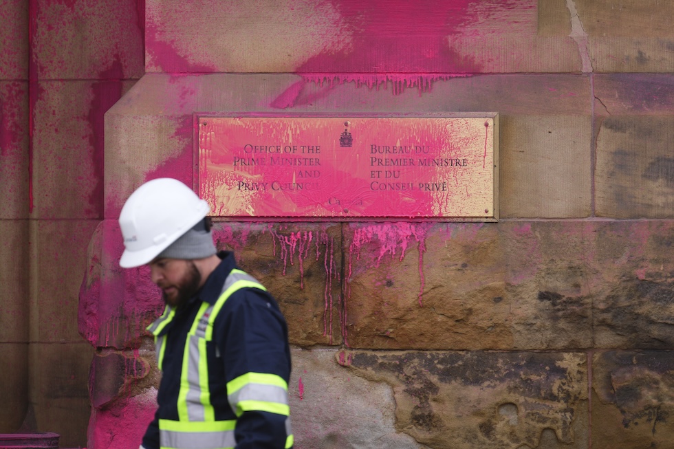 Un addetto alle pulizie davanti all'ufficio del primo ministro Justin Trudeau, sporcato con della vernice rosa in segno di protesta