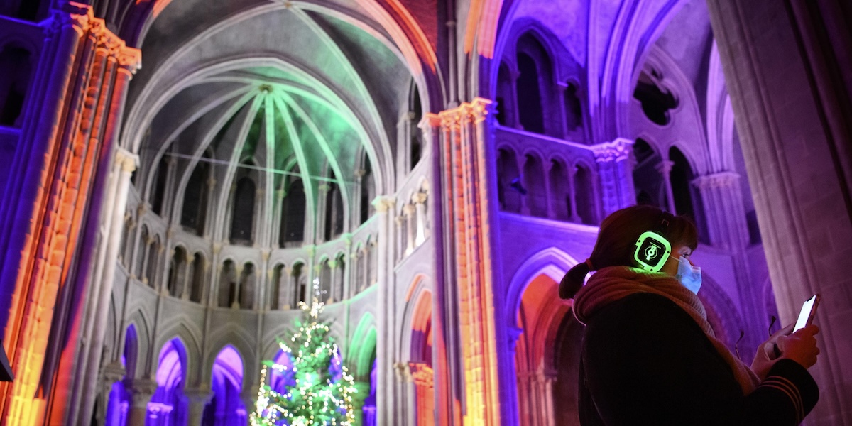 Una persona con le cuffie per ascoltare la musica illuminate dentro una cattedrale