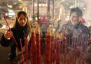 Due persone pregano e accendono dei bastoncini di incenso al tempio di Mazu Miao