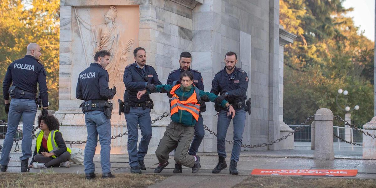 Foto di un attivista ambientalista all'Arco della Pace di Milano portato via dalla polizia