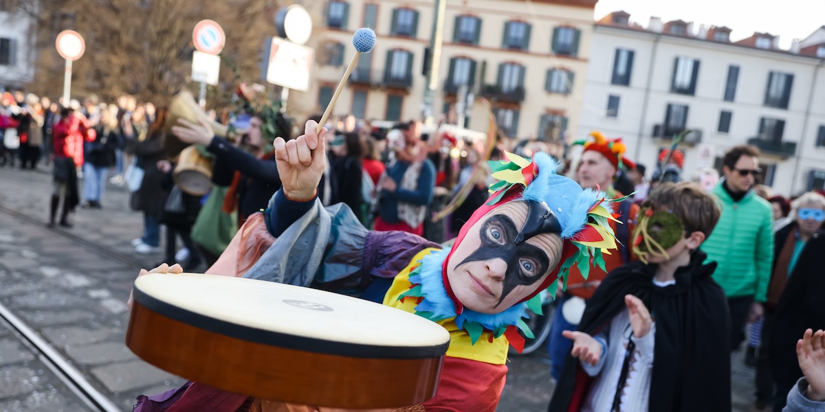 Una persona in maschera con un tamburello durante i festeggiamenti del Carnevale alla Darsena di Milano, il 25 febbraio del 2023