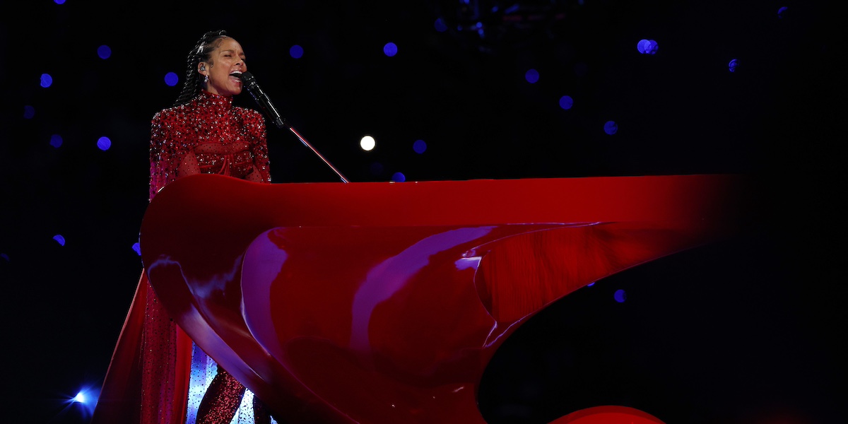 Alicia Keys, vestita di rosso, canta e suona un pianoforte rosso durante la sua performance all'Halftime Show del Super Bowl del 2024