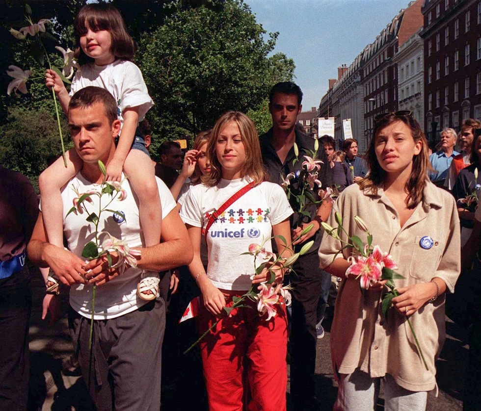 Robbie Williams con Nicole Appleton e Melanie Blatt a una marcia a Londra nel 1998 per una campagna contro le mine antiuomo. Sulle spalle ha la nipote di Appleton, Rachel