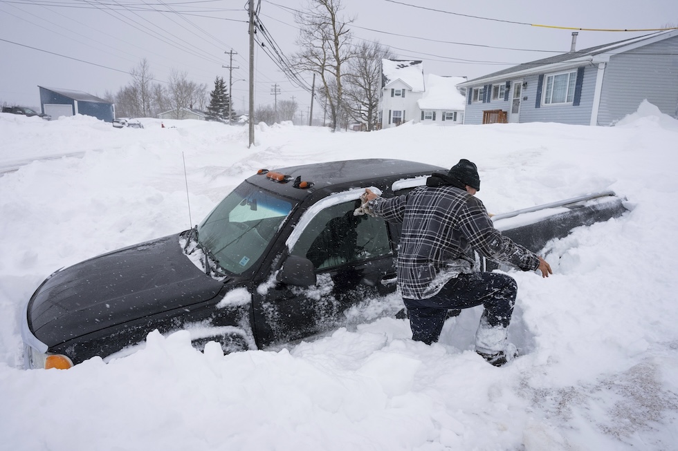 Un uomo cerca di liberare la neve accumulata attorno al suo pick-up dopo una nevicata in Nuova Scozia (Sydney, Canada)