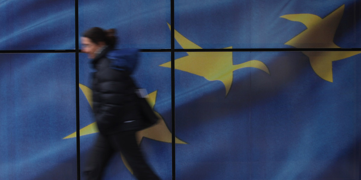 La foto di una persona che cammina davanti a una bandiera dell'Unione europea