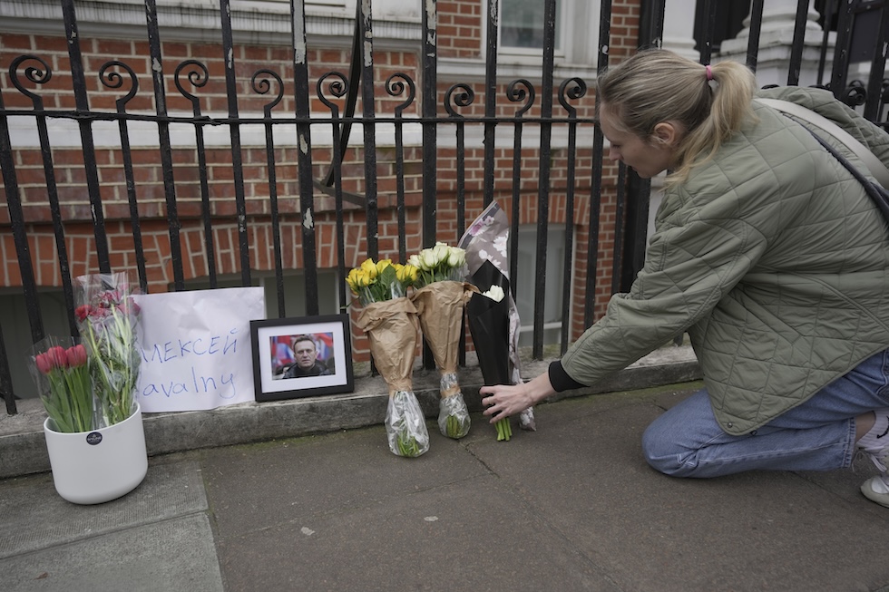 Una donna posa dei fiori per Navalny fuori dall'ambasciata russa a Londra