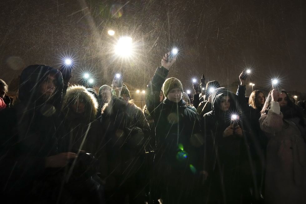 Un gruppo di persone con le torce dei cellulari accese rende omaggio ad Alexei Navalny al memoriale delle vittime della repressione politica a San Pietroburgo. 16 febbraio 2024
