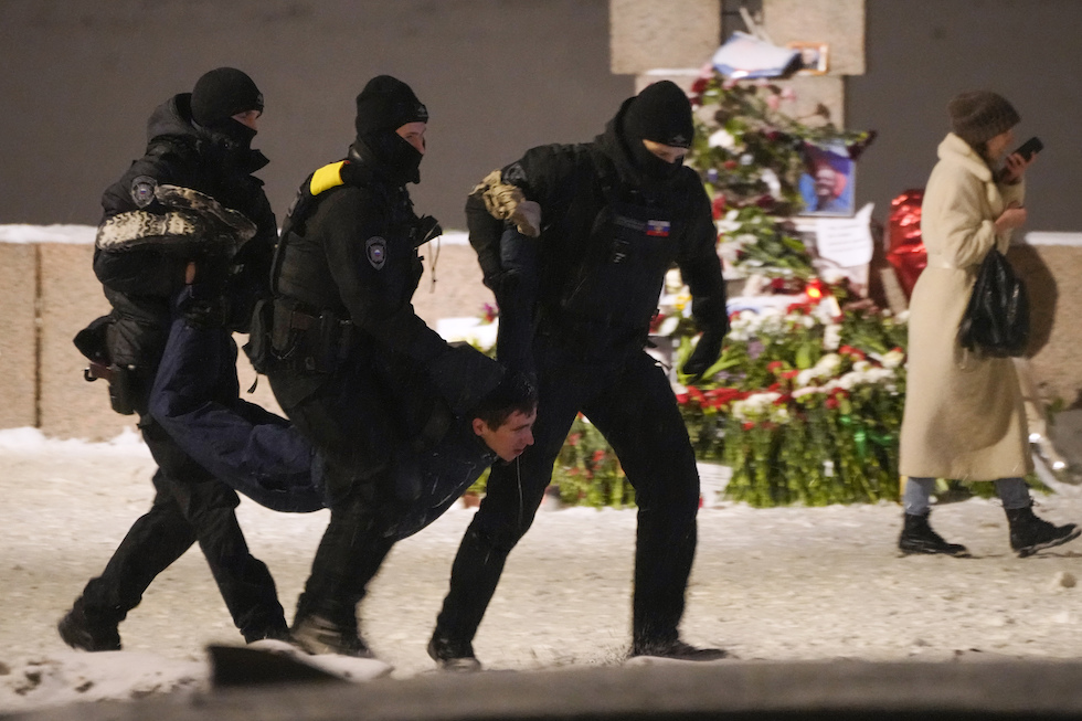 Una persona trascinata via dalla polizia per aver messo fiori in memori di Navalny a San Pietroburgo, il 16 febbraio 2024