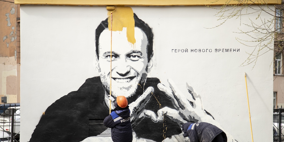 Un uomo copre un ritratto di Navalny con della vernice a San Pietroburgo, nel 2021 (AP Photo/Ivan Petrov)