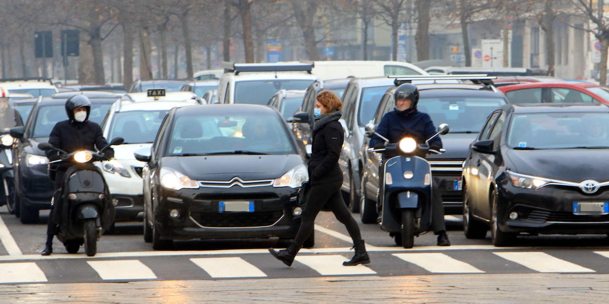 Persone che indossano mascherine sul viso nel traffico di Milano