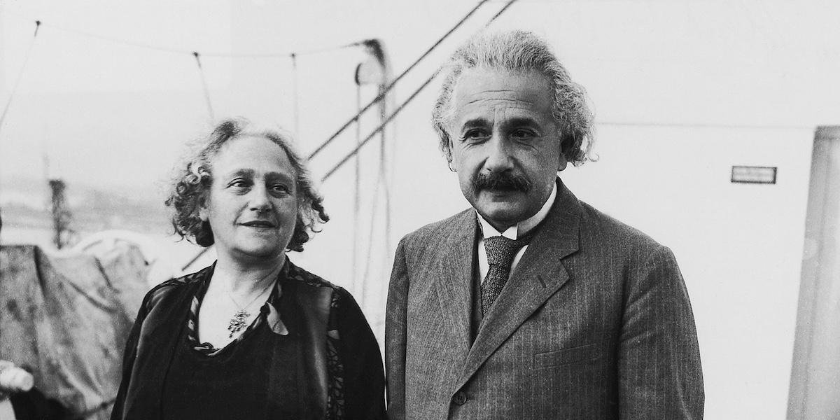 Elsa e Albert Einstein, in piedi e vicini, fotografati frontalmente, accennano un sorriso senza volgere lo sguardo verso l'obiettivo