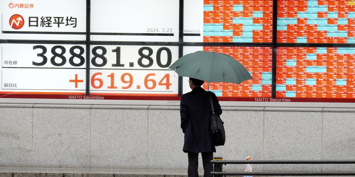Foto di una persona a Tokyo si ferma a guardare gli schermi con l'andamento del Nikkei che si avvicina verso il record storico del 1990
