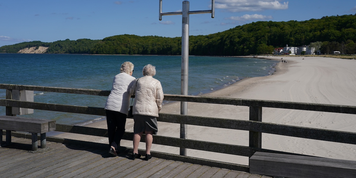 Due donne anziane guardano una spiaggia da un pontile
