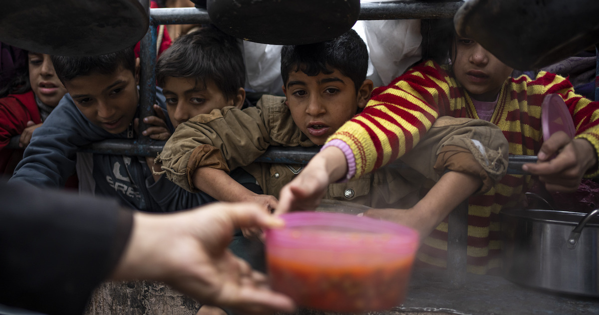 Bambini palestinesi in fila per ricevere un pasto a Rafah, nel sud della Striscia di Gaza