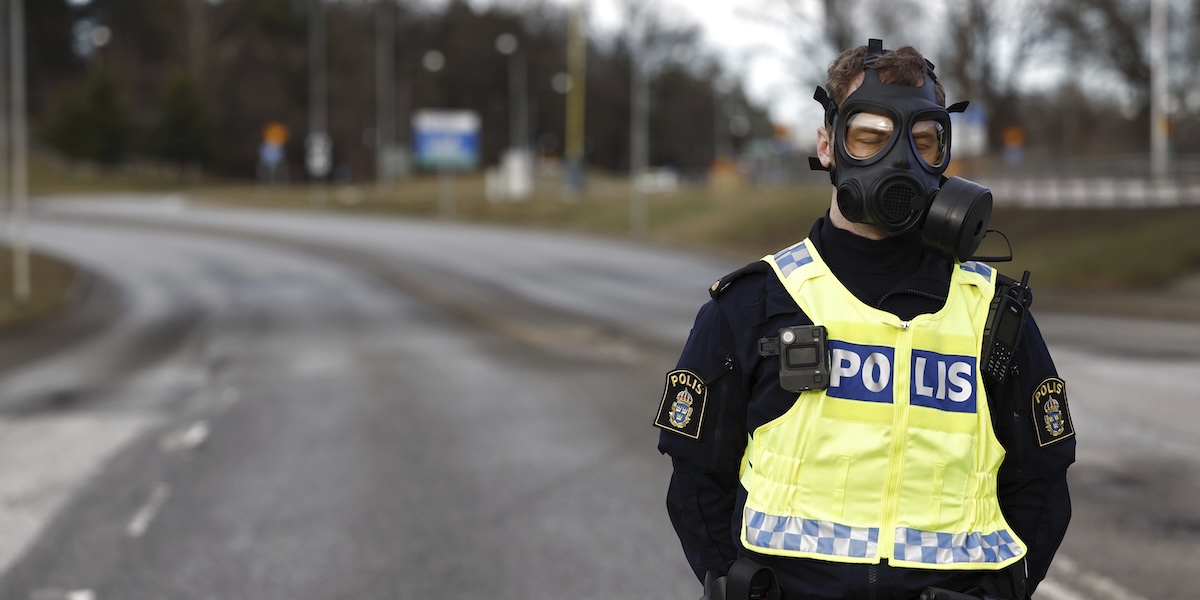 Un poliziotto svedese con addosso una maschera antigas