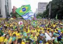 Foto della folla alla manifestazione con una bandiera del Brasile e una bandiera di Israele in primo piano