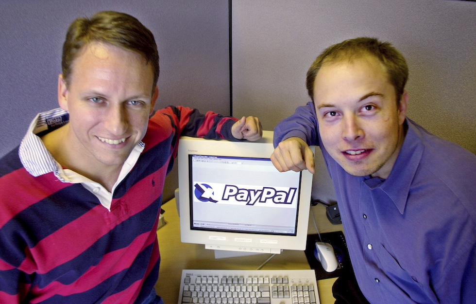 Thiel e Musk in posa vicino a un monitor che mostra il logo di PayPal