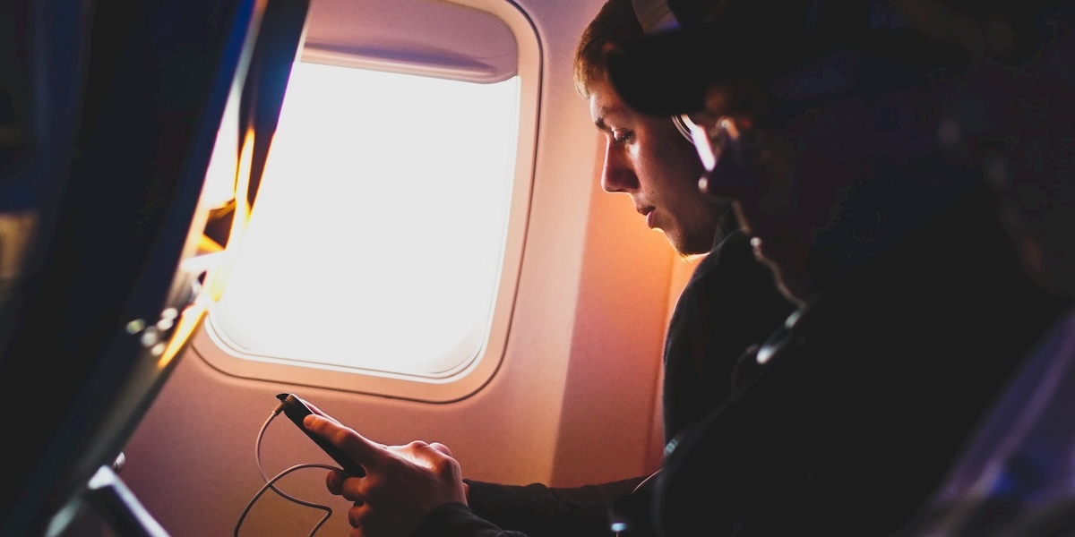 Un ragazza guarda il cellulare a bordo di un aereo