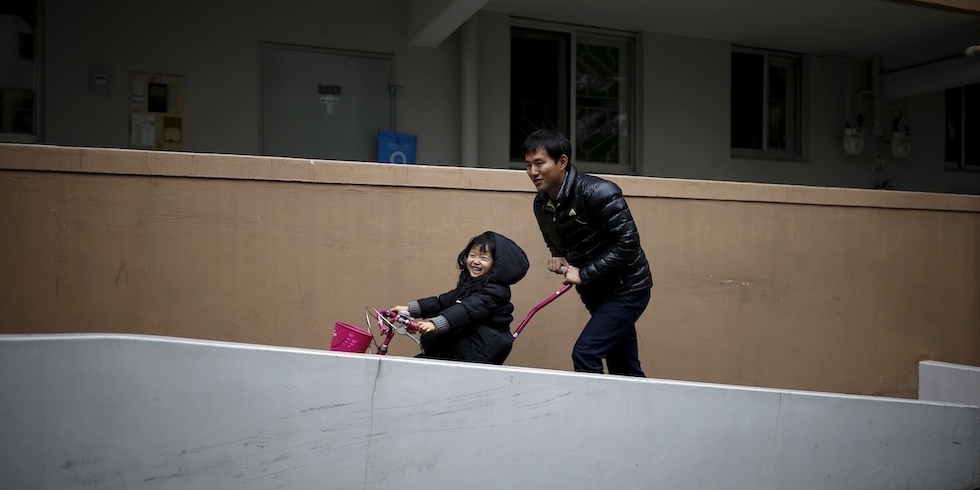 Un uomo sudcoreano spinge la figlia, una bambina piccola, su una bicicletta