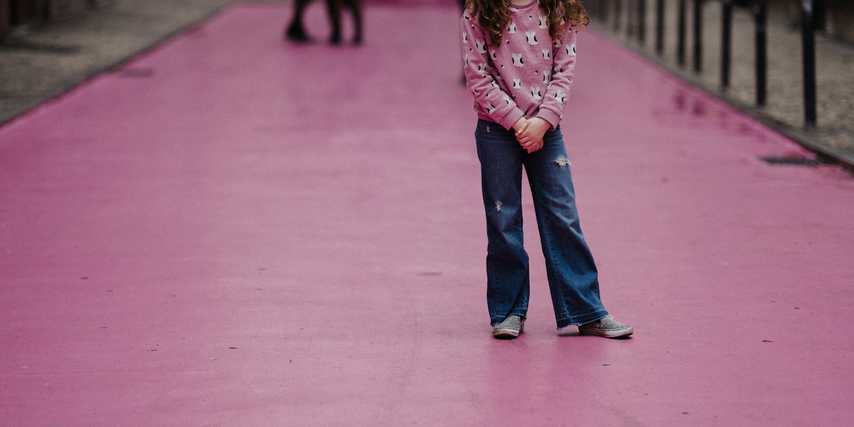 Il corpo di una bambina in posa per una foto, con un jeans e una maglietta: la foto è tagliata in modo da non mostrarne il volto