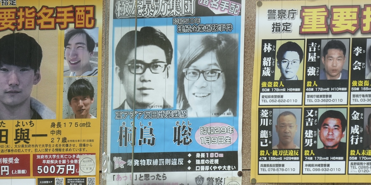 Un poster con due foto di Satoshi Kirishima e altri ricercati appeso fuori da una stazione di polizia a Tokyo, il 2 febbraio del 2024