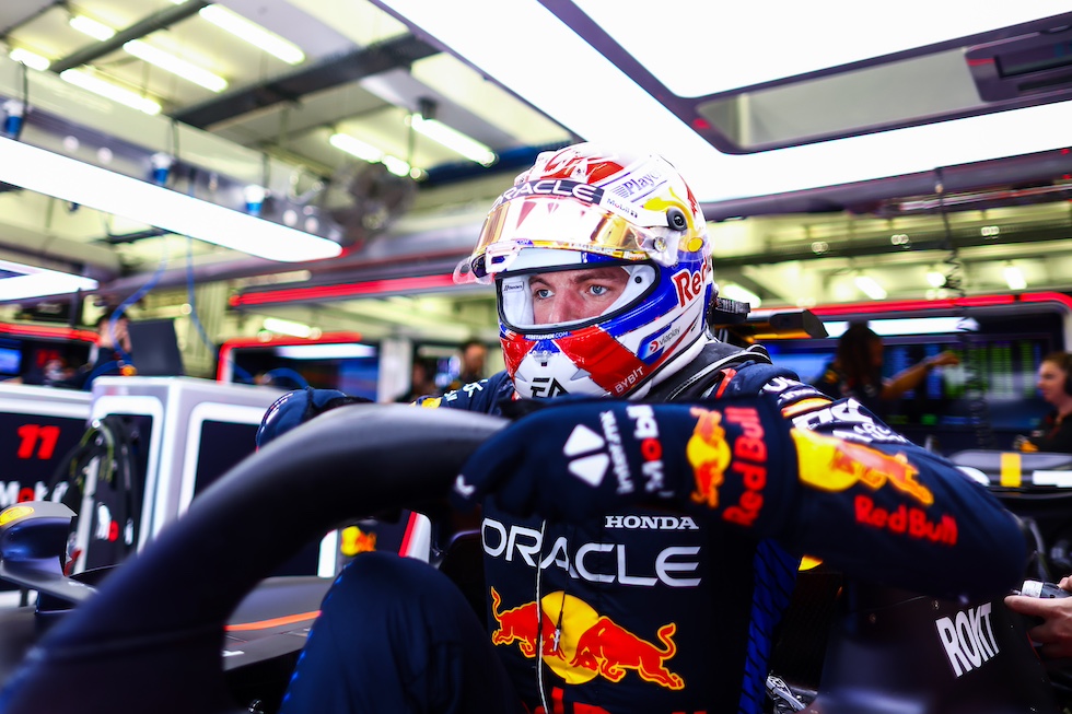 Verstappen, con il casco in testa, mentre sale o forse mentre scende dalla macchina parcheggiata nel box