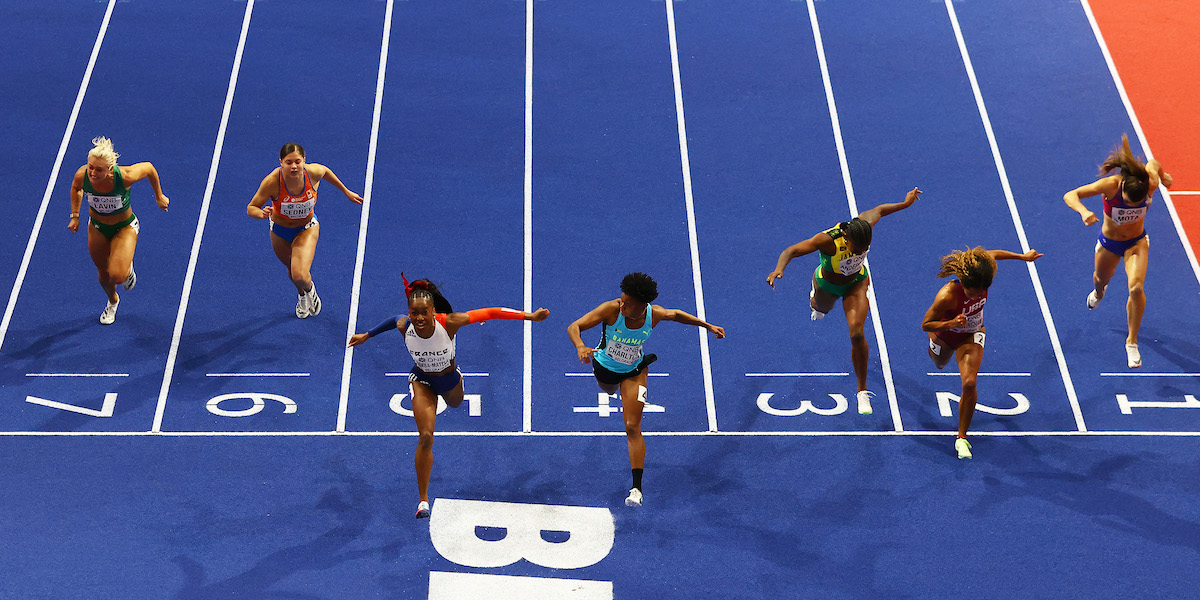 Foto di atlete che corrono i sessanta metri su una pista blu