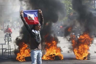 Un manifestante mostra una bandiera di Haiti durante una protesta per chiedere le dimissioni del primo ministro Ariel Henry.